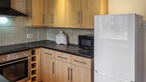 Una cocina con armarios de madera, horno empotrado, microondas y refrigerador.