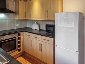 A kitchen with wooden cabinets, a built-in oven, a microwave, and a refrigerator.