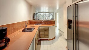 A modern kitchen with a stainless steel refrigerator, a coffee machine, and a built-in oven.