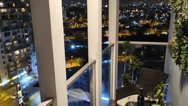 Un balcon avec une table et des chaises, une bouteille de vin et une plante en pot.