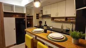 Une cuisine compacte avec un îlot central en bois, deux suspensions et des chaises jaunes.