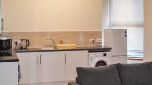 Une cuisine compacte équipée d’un évier, d’une machine à café, d’un lave-linge et d’un réfrigérateur.