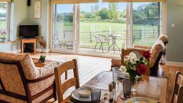 A dining area with a table set for four, a television, and a view of a fenced outdoor area.