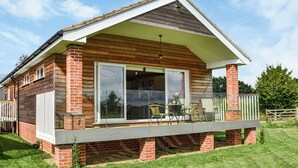 A two-story house with a balcony, large sliding glass doors, and a brick exterior. - An ideal destination for relaxation, comfort, and immersion in nature’s beauty. (Old Buckenham)