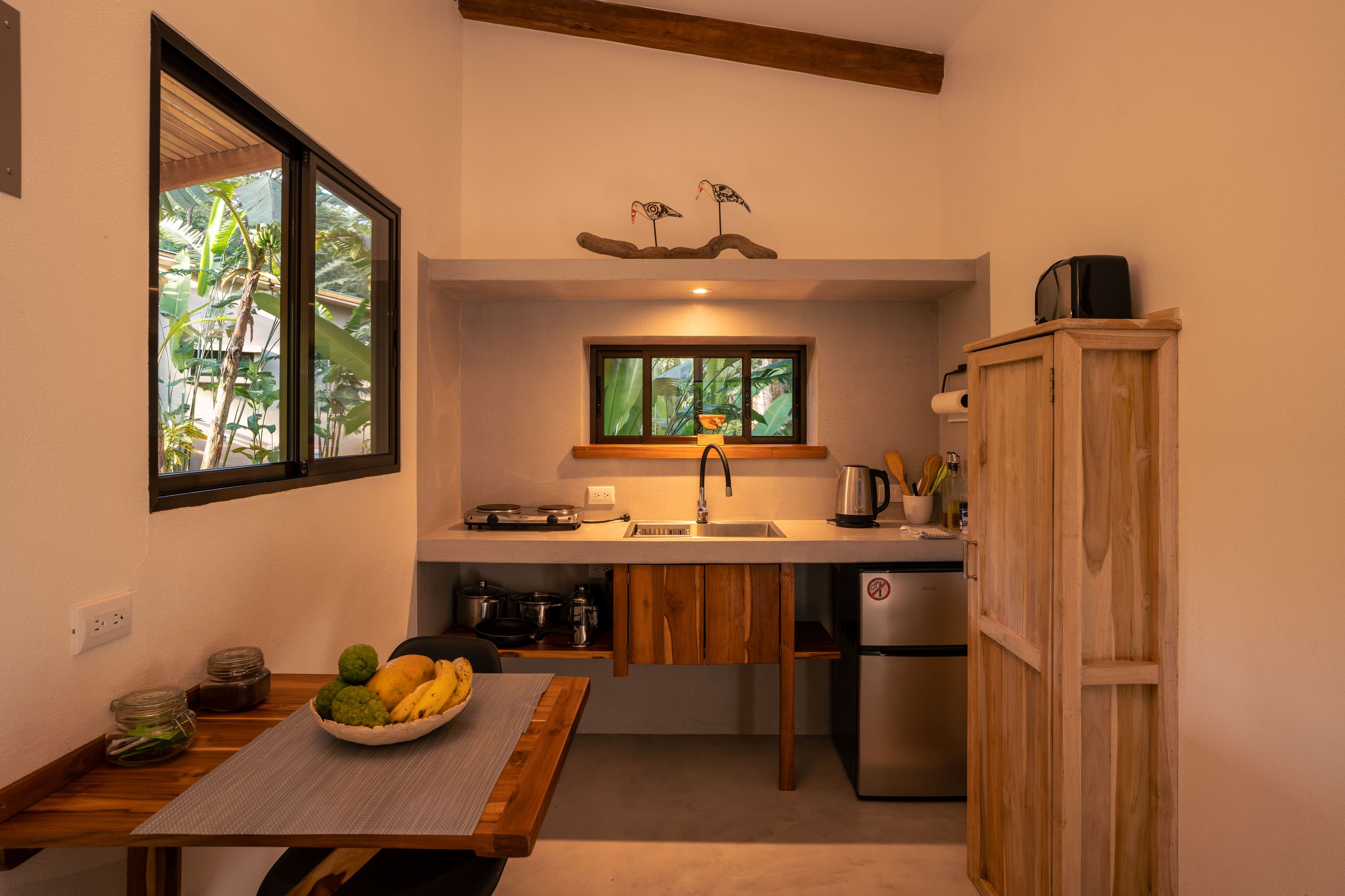 Cocina compacta con estufa integrada, lavamanos y refrigerador.