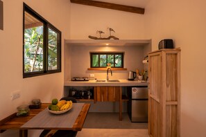 A compact kitchen with a built-in stove, a sink, and a refrigerator. - Pájaros · Bright Jungle Cabin + Pool · Walk to Beach · Sleeps 3 (Cóbano)