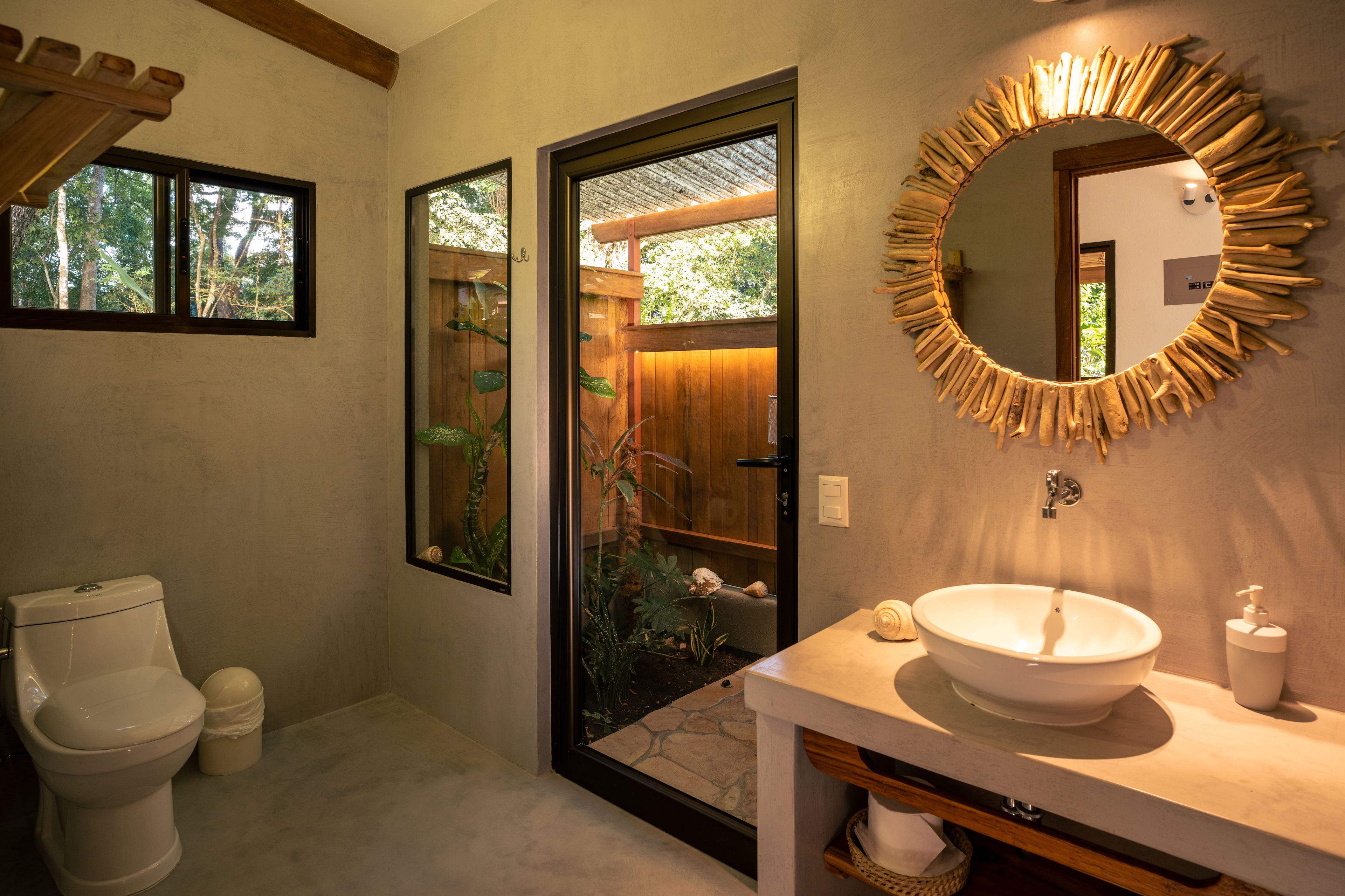 Een badkamer met toilet, wastafel en spiegel met een bijzondere houten lijst.
