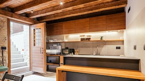 A modern kitchen with wooden cabinets, a built-in oven, and a large island. - Casa del Vicario (Fagagna)