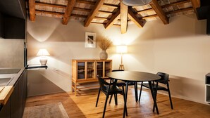 A dining area with a wooden table and chairs, a cabinet with glass doors, and a vase with dried plants. - Casa del Vicario (Fagagna)