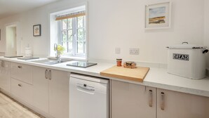 Cozinha moderna com máquina de lavar louça, cozedoura para pão e janela com vista para o verde.