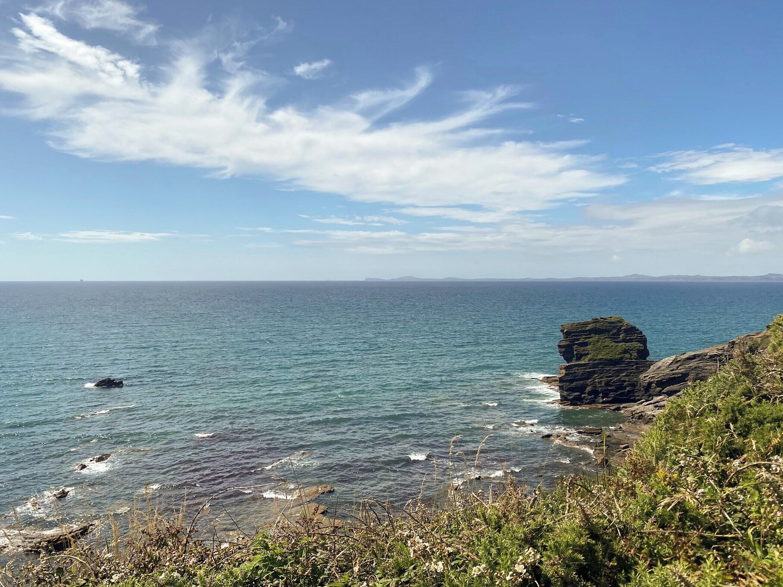Un paysage côtier caractérisé par une formation rocheuse imposante et une mer calme.