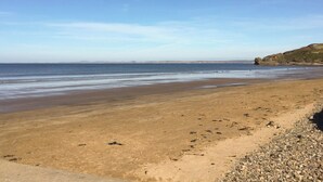 Ein Strand mit Kiesstrand und in der Ferne felsigen Klippen.