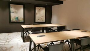 A conference room with a long table, six chairs, and two abstract paintings on the wall.