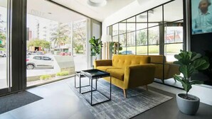 A modern interior with a yellow sofa, a small table, and a potted plant.