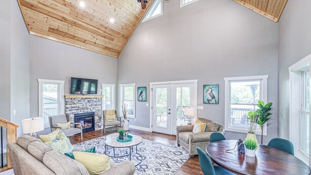 A spacious living room with a fireplace, a dining area, and a ceiling fan.