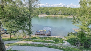 A lakeside property with a dock, a boat, and a small building.