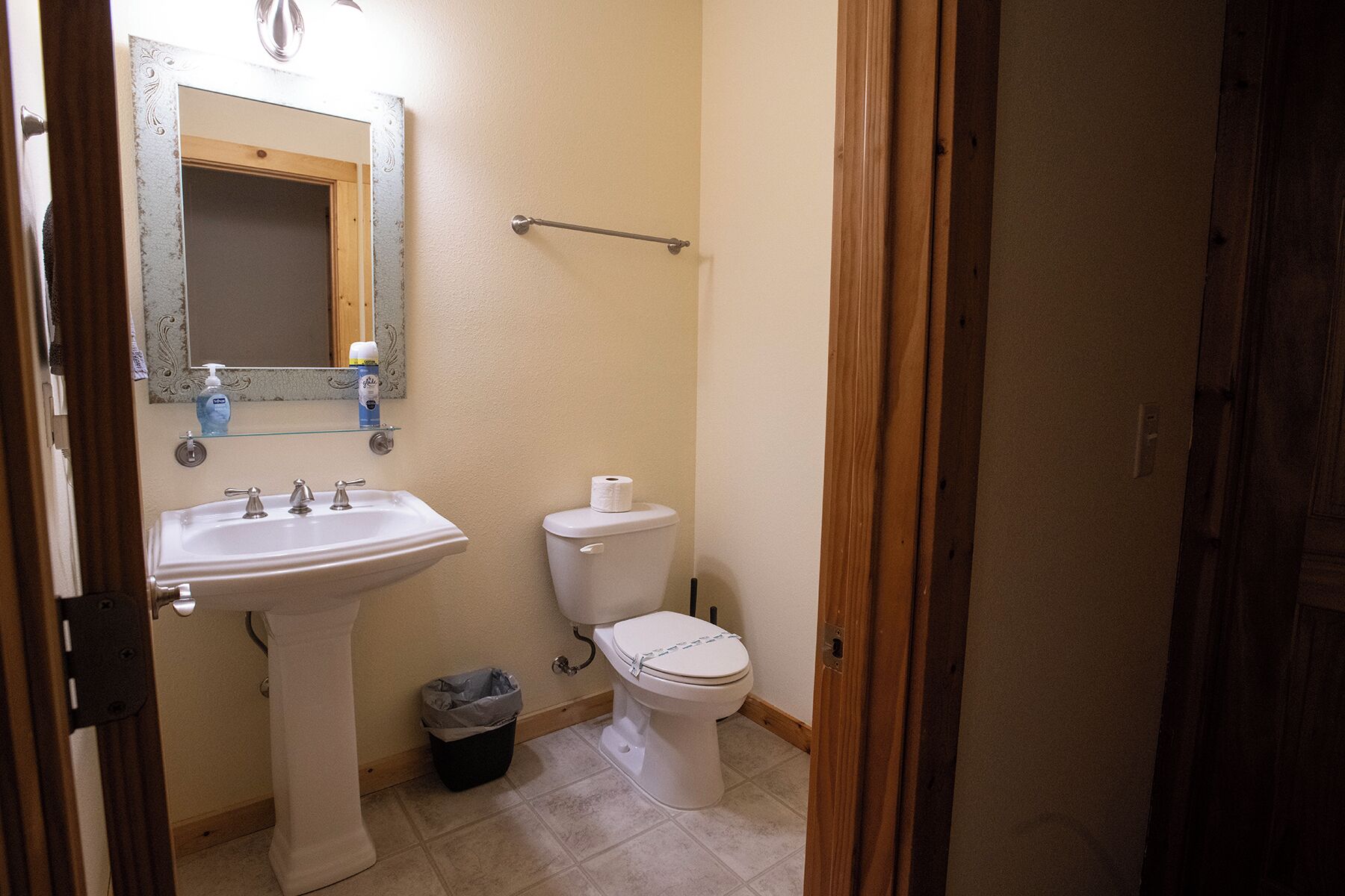 A bathroom with a white sink, a toilet, and a mirror with a wooden frame.