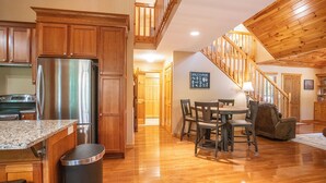 A spacious kitchen with wooden cabinets, a stainless steel refrigerator, and a granite countertop. - Redbud Retreat ~ Rustic family friendly cabin with New Hot Tub in Townsend! (Townsend)