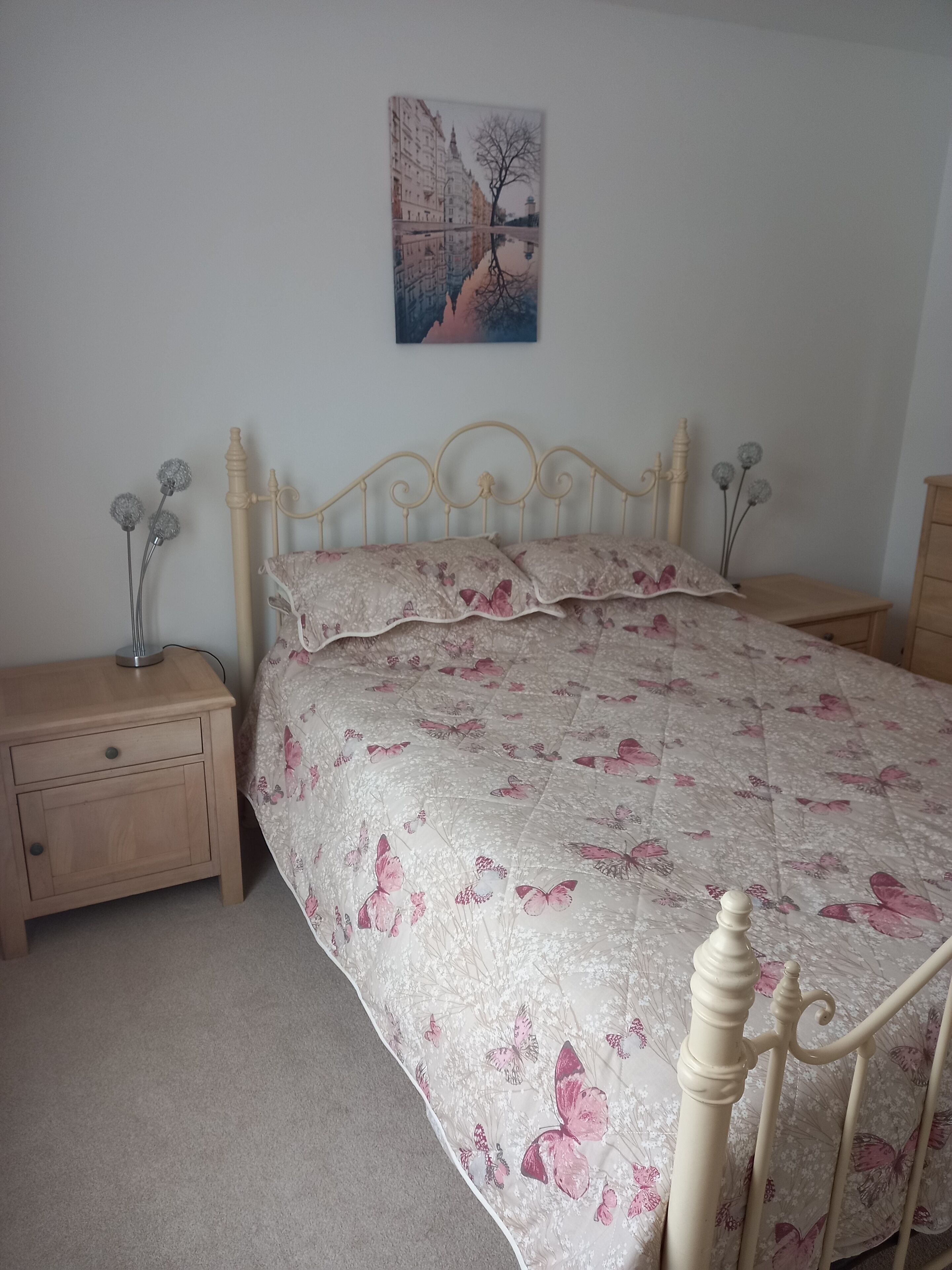 A bedroom with a bed, a nightstand, a dresser, and a wall-mounted painting.