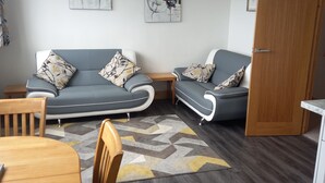 Un salon moderne avec un canapé gris, une table à manger en bois et un tapis à motifs.