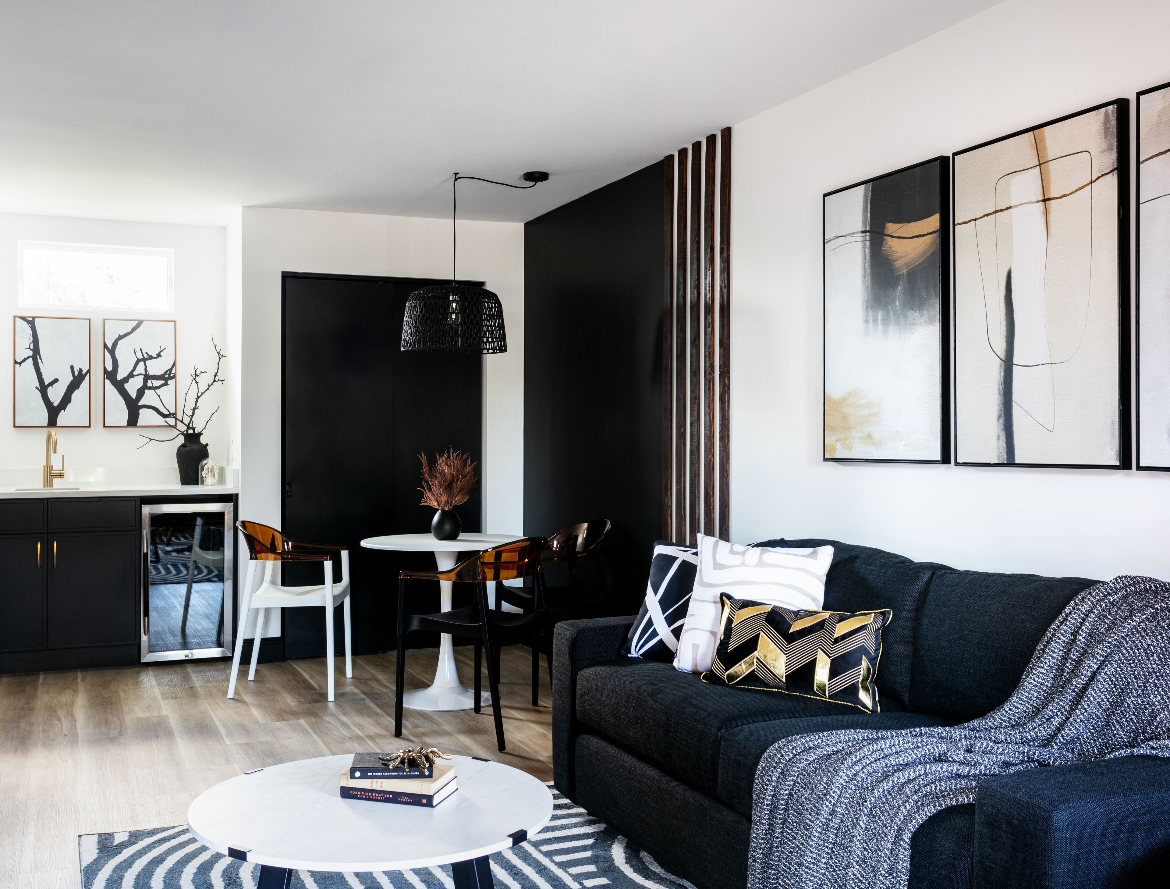 A modern living room with a black sofa, a round coffee table, and a dining area with a white table and chairs.