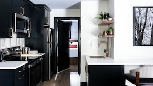 A modern kitchen with black cabinetry, stainless steel appliances, and a white countertop. -  The Cove At Salem (Salem)