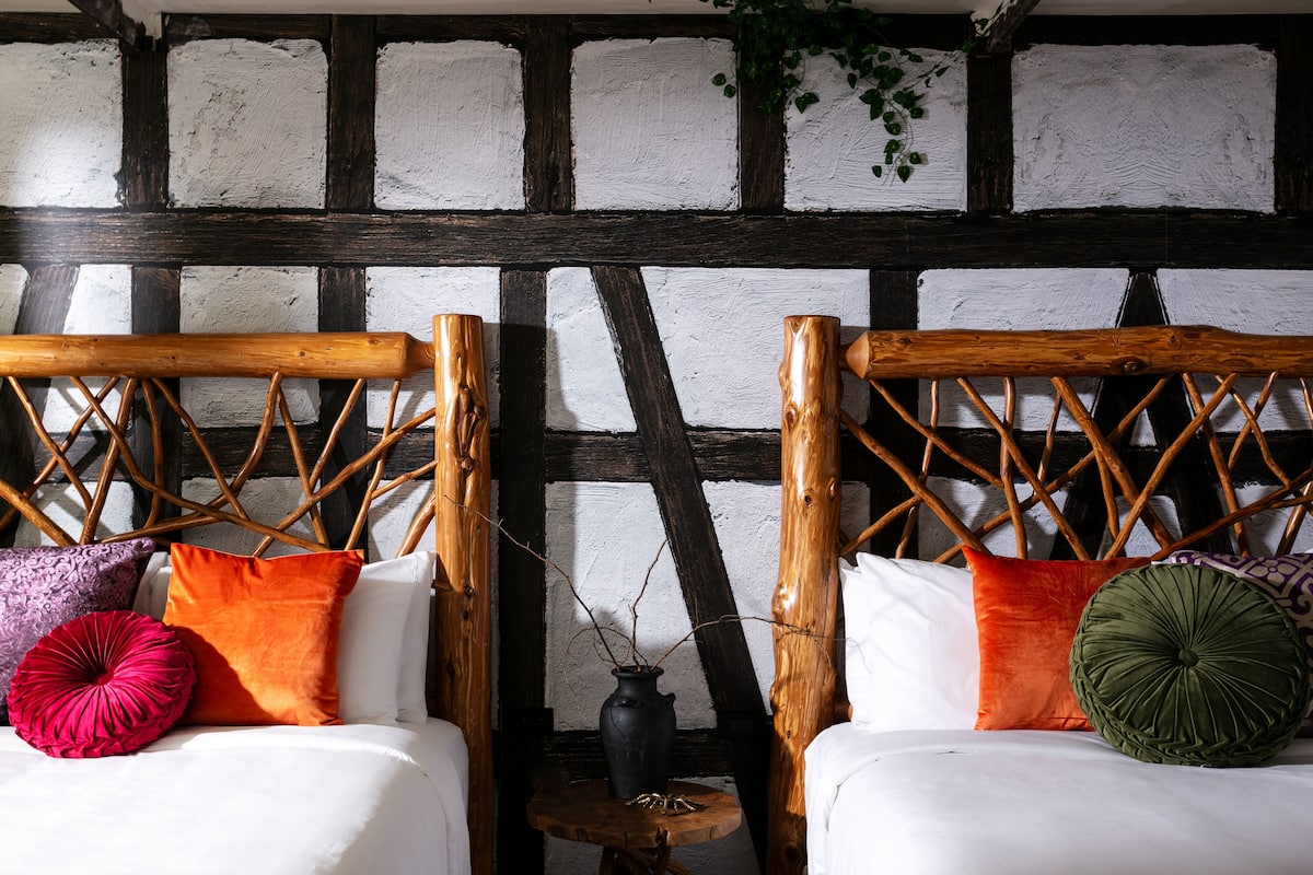 A room with two wooden beds with lattice headboards, white bedding, and colorful pillows.