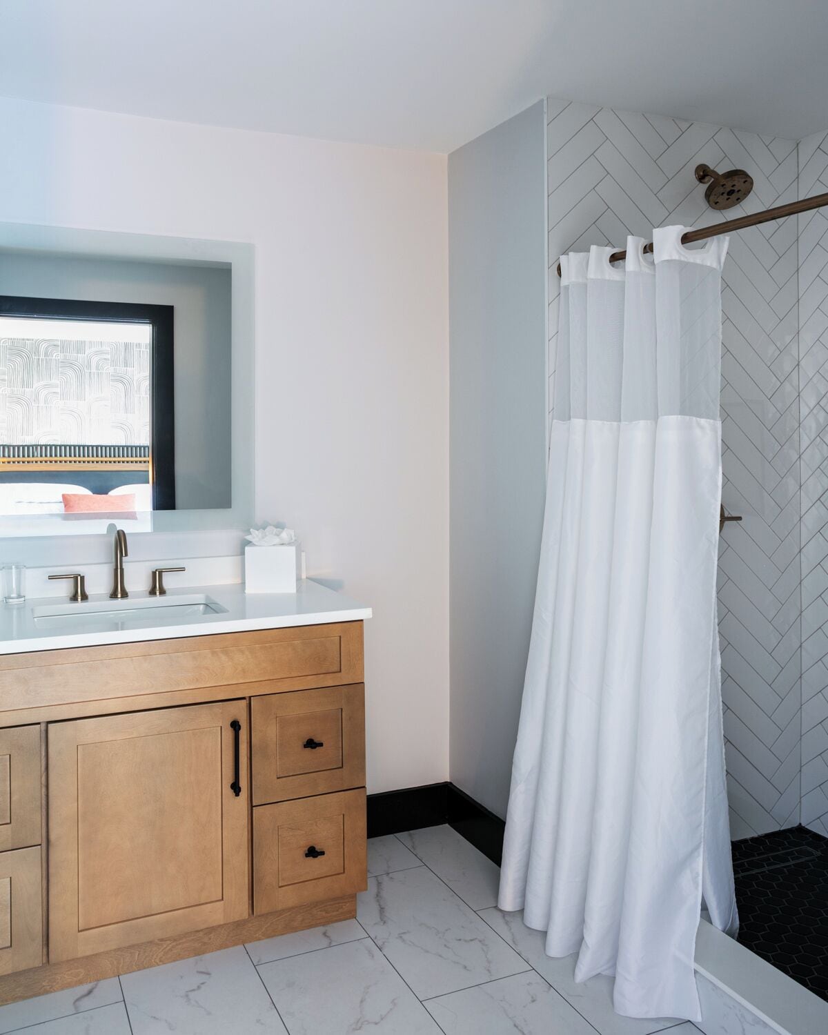 A modern bathroom with a wooden vanity, a white sink, and a shower curtain.