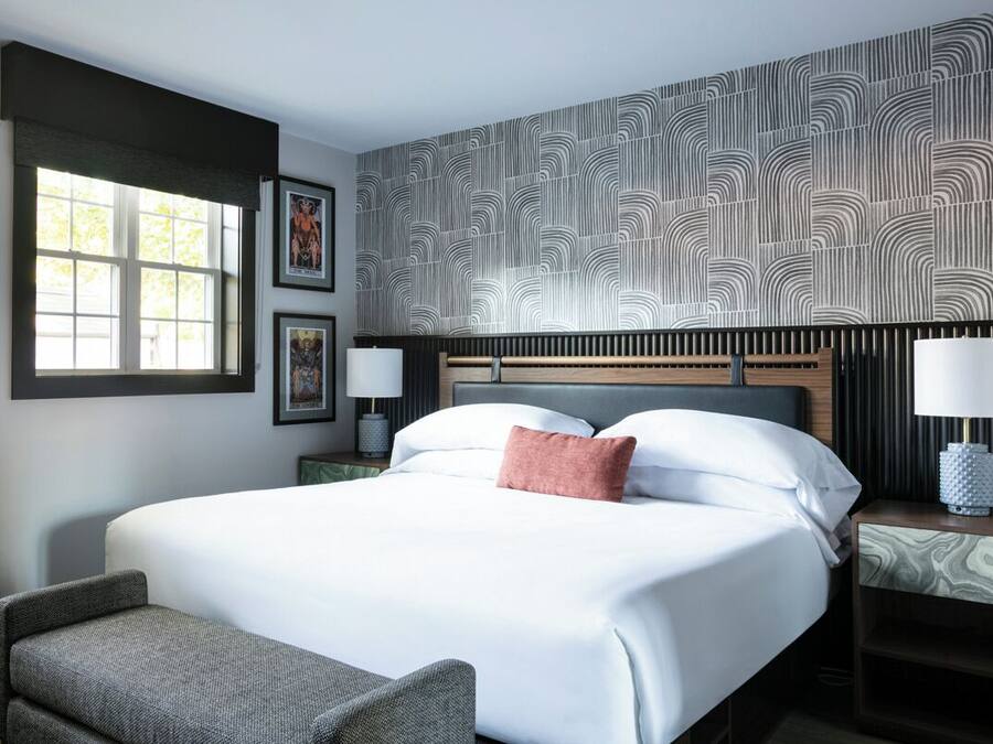 Une chambre d’hôtel avec un grand lit, une fenêtre et un mur décoré de motifs.
