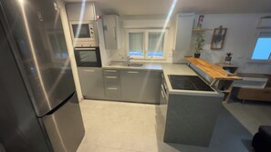 A modern kitchen with stainless steel appliances, a built-in oven, and a central island with a stovetop.