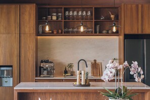Cucina con pensili in legno, una macchina da caffè, un erogatore d'acqua e una ciotola di frutta sul bancone.