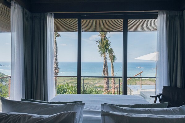A room with a large window, a bed, and a chair.