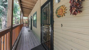 A wooden deck with a glass door leading to a covered porch. - Hunter's Lodge by Ruidoso Vacation Rentals (Ruidoso)