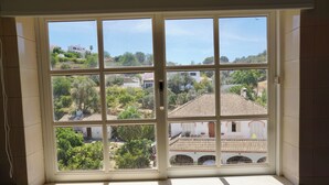 Una ventana con vista a una zona residencial, que incluye casas y vegetación.
