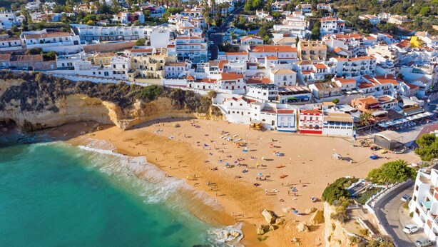 Vista aérea de un pueblo costero con playa, edificios y una carretera.