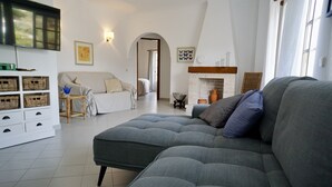 Una sala de estar moderna con un sofá gris, un mueble blanco y una chimenea.