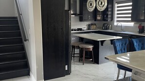 A modern kitchen with a central island, dark cabinetry, and a staircase on the left. - Luxury getaway with pool and hot tub - family retreat  (Windsor)