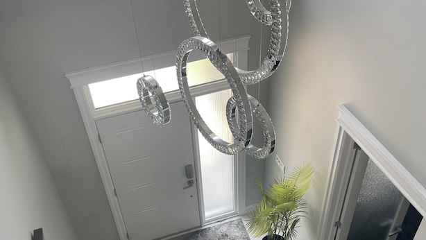 A staircase with a chandelier, a potted plant, and a mirror reflecting the room. - Luxury getaway with pool and hot tub - family retreat  (Windsor)