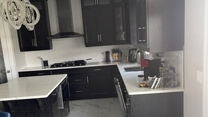 A modern kitchen with dark cabinets, a marble countertop, and a built-in island. - Luxury getaway with pool and hot tub - family retreat  (Windsor)