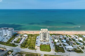 An aerial view of a coastal hotel with a parking lot, a beach, and ocean views. - Oceanfront Penthouse #11B by Distinctive Beach Rentals (Ormond Beach)