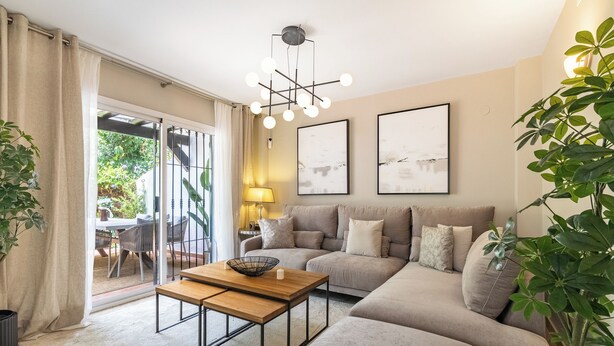 Un salon moderne avec un canapé, une table basse et une lampe. Deux œuvres d’art encadrées ornent le mur, et une plante est placée dans un coin.