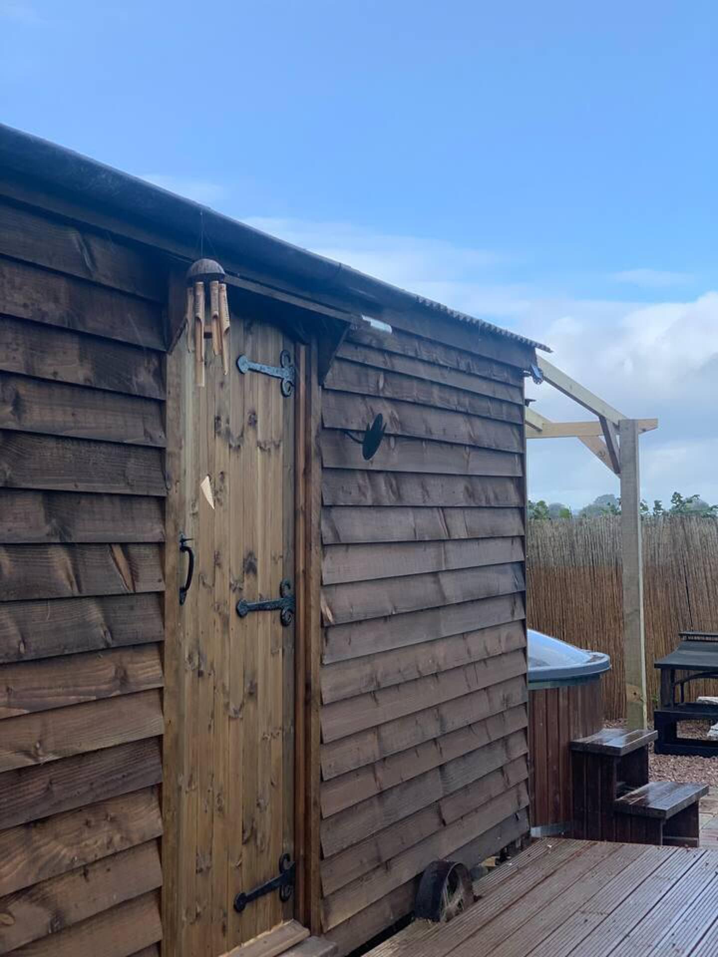 A wooden cabin with a door, a small porch, and a table.