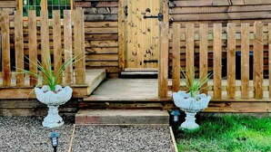 A rustic wooden cabin with a wooden door and two white birdbaths in front. - Cute and Cosy Shepard hut With Wood Fuel hot tub (Kington)