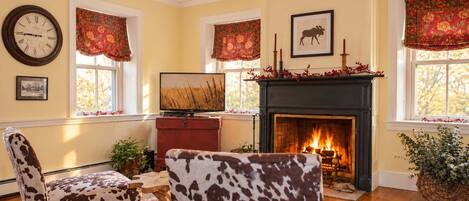 A cozy living room with a fireplace, a television, and a clock on the wall.