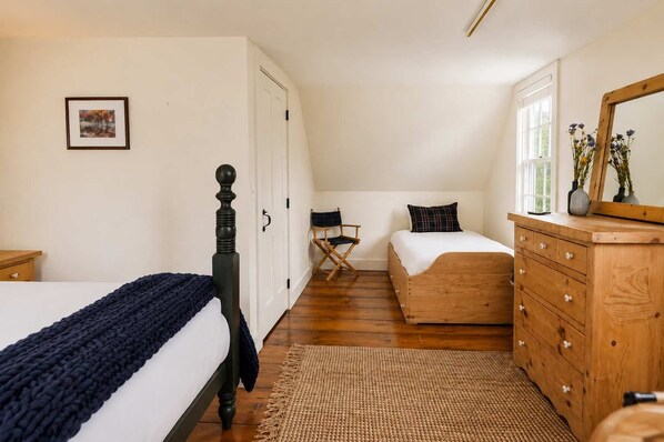 A bedroom with a bed, a dresser, a chair, and a window.