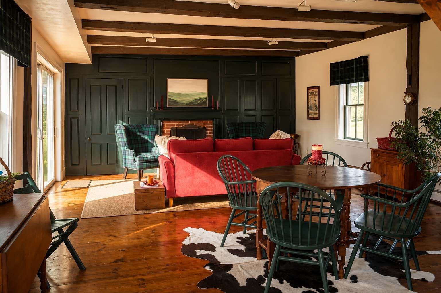 A cozy living room with a red sofa, green chairs, a wooden dining table, and a fireplace.