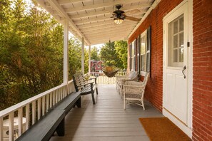 A covered porch with a bench, wicker chairs, and a hanging chair.