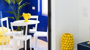 A modern room with a blue accent wall, white furniture, a yellow vase, and a unique yellow planter.