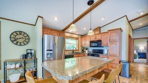 A kitchen with a granite island, wooden cabinets, and a clock on the wall.