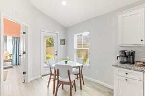 A modern kitchen with white cabinets, a granite countertop, and a built-in coffee maker.